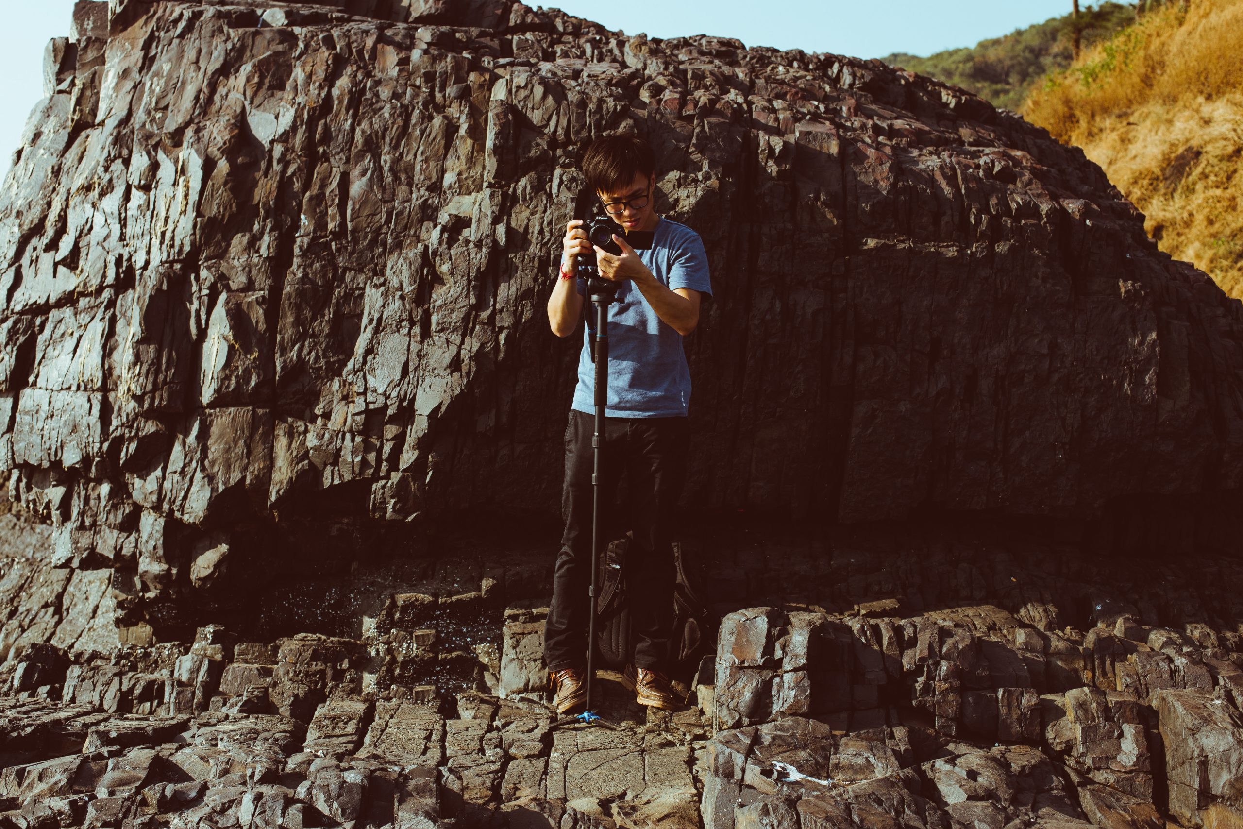 man holding camera while standing on cliff during daytime