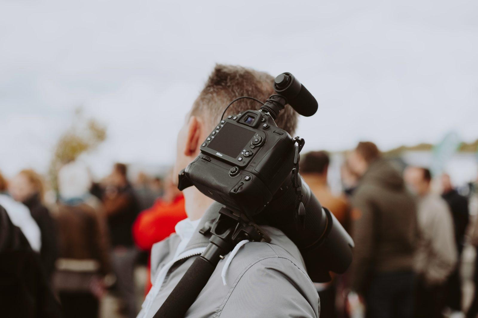 man with black DSLR camera on his shoulder